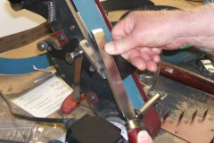 David Hutcheson using a belt tool with the tool guide to sharpen a flat skew.